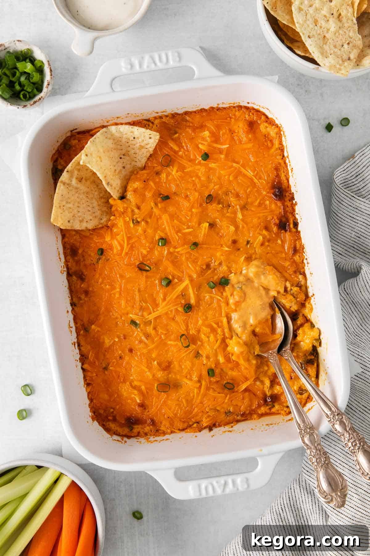 An inviting overhead view of the warm, bubbly dairy-free buffalo chicken dip in a rustic baking dish, garnished with vibrant green onions, ready to be served.