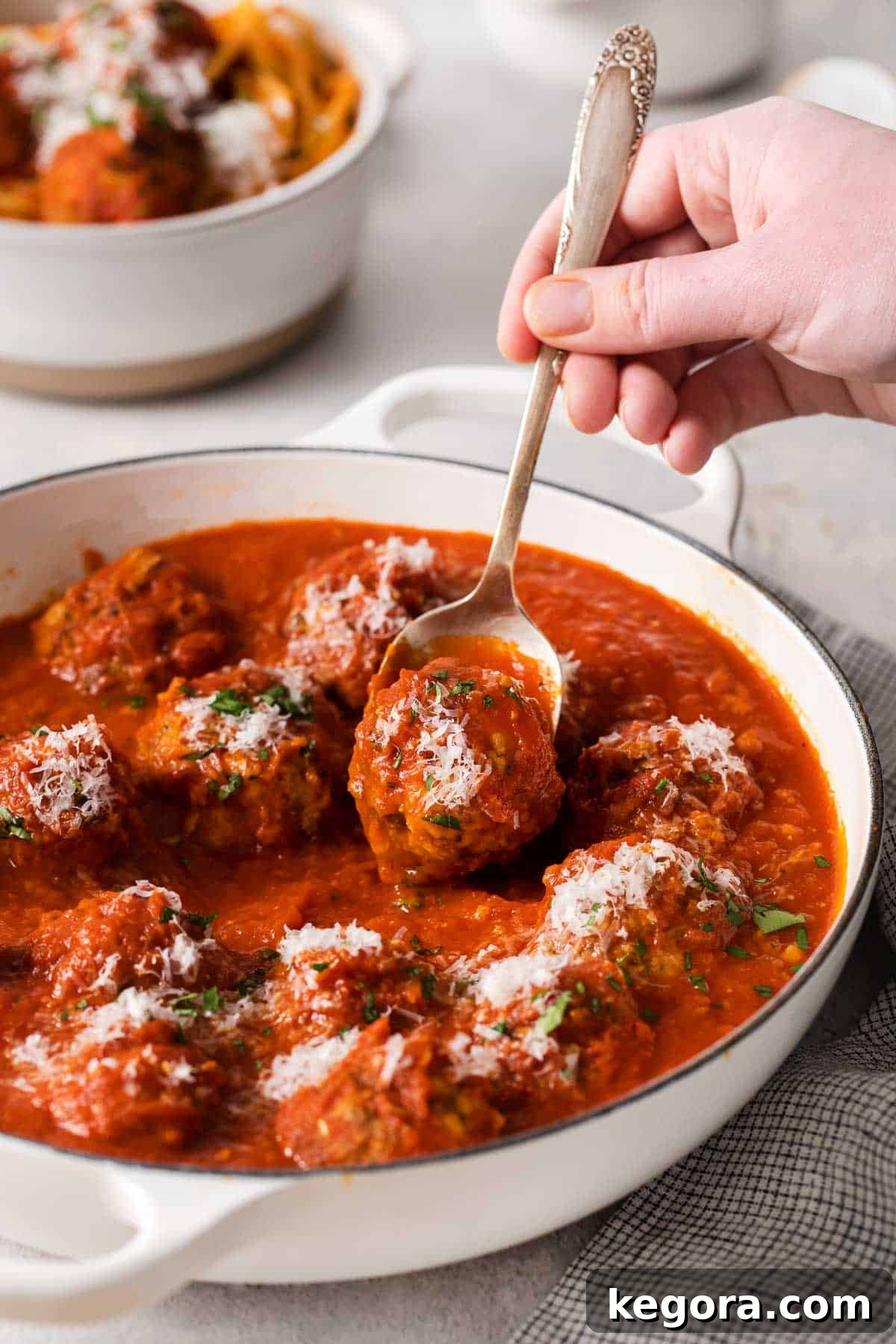 Traditional Italian Gluten Free Meatballs 11 Gluten-free meatballs in a serving dish and a fork reaching in to pick up a meatball.