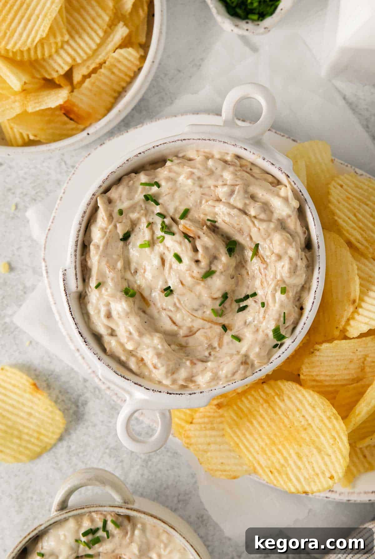 Ultimate Caramelized Onion Dip 3 Creamy homemade caramelized onion dip in a rustic serving bowl, perfectly accompanied by a generous pile of crispy potato chips, artfully arranged and ready to be served as an enticing appetizer.