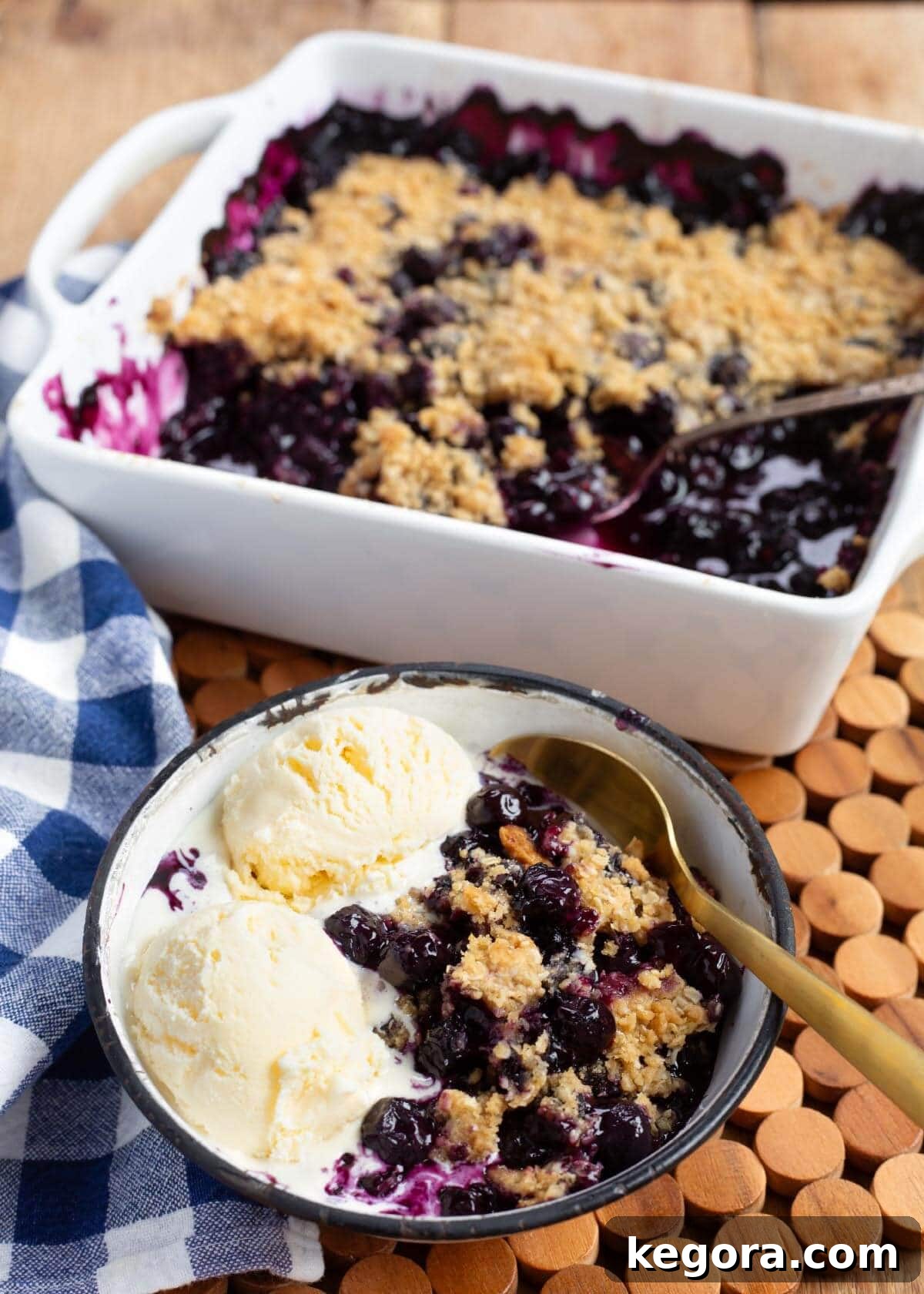 Easy Blueberry Crisp in baking dish and a bowl with vanilla ice cream and spoon
