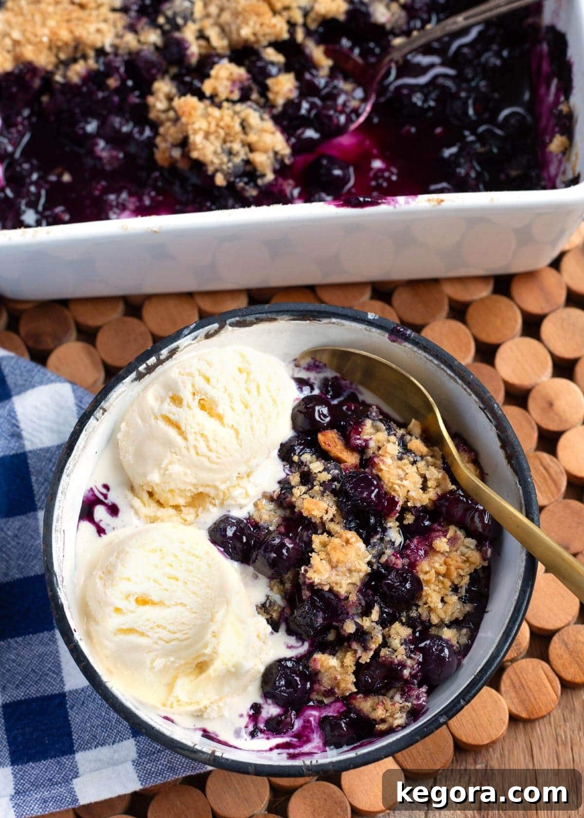 Easy Blueberry Crisp in baking dish and a bowl with ice cream and spoon, ready to be served