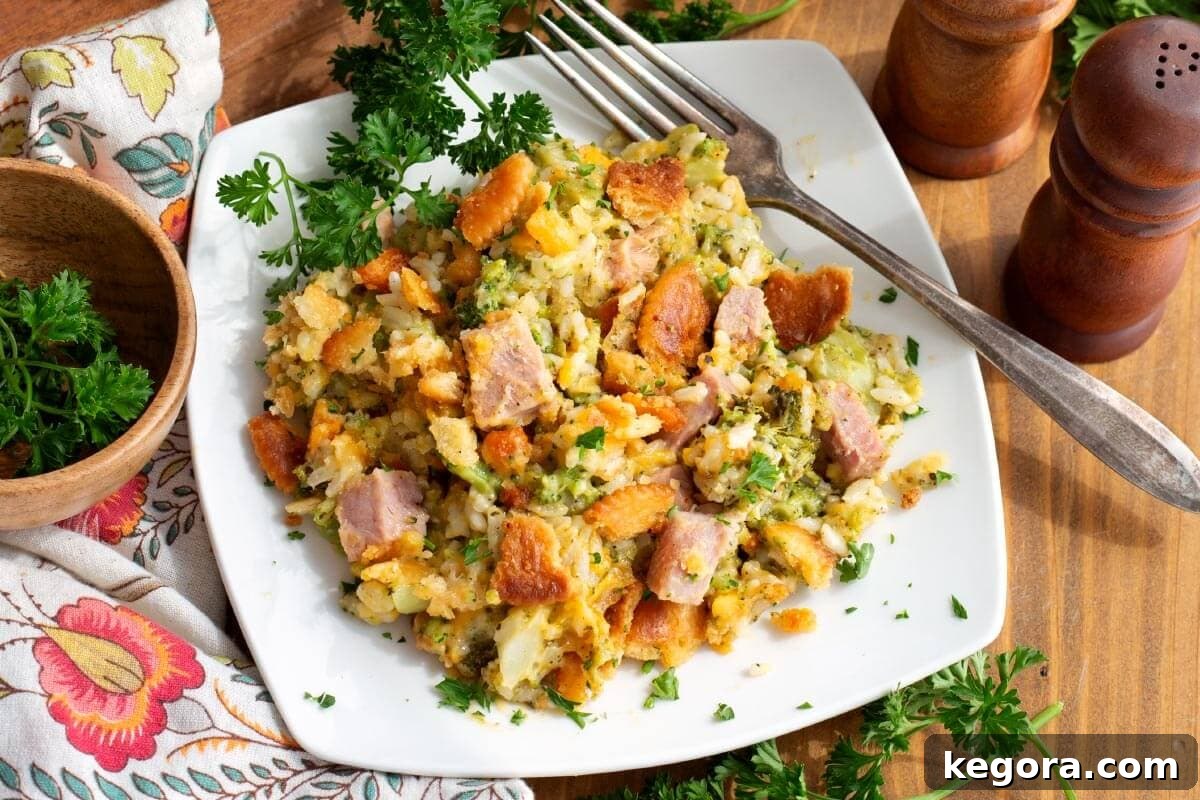 Hearty Ham and Broccoli Rice Bake 3 Ham and Broccoli Rice Casserole served on a white plate with a side of fresh parsley garnish.