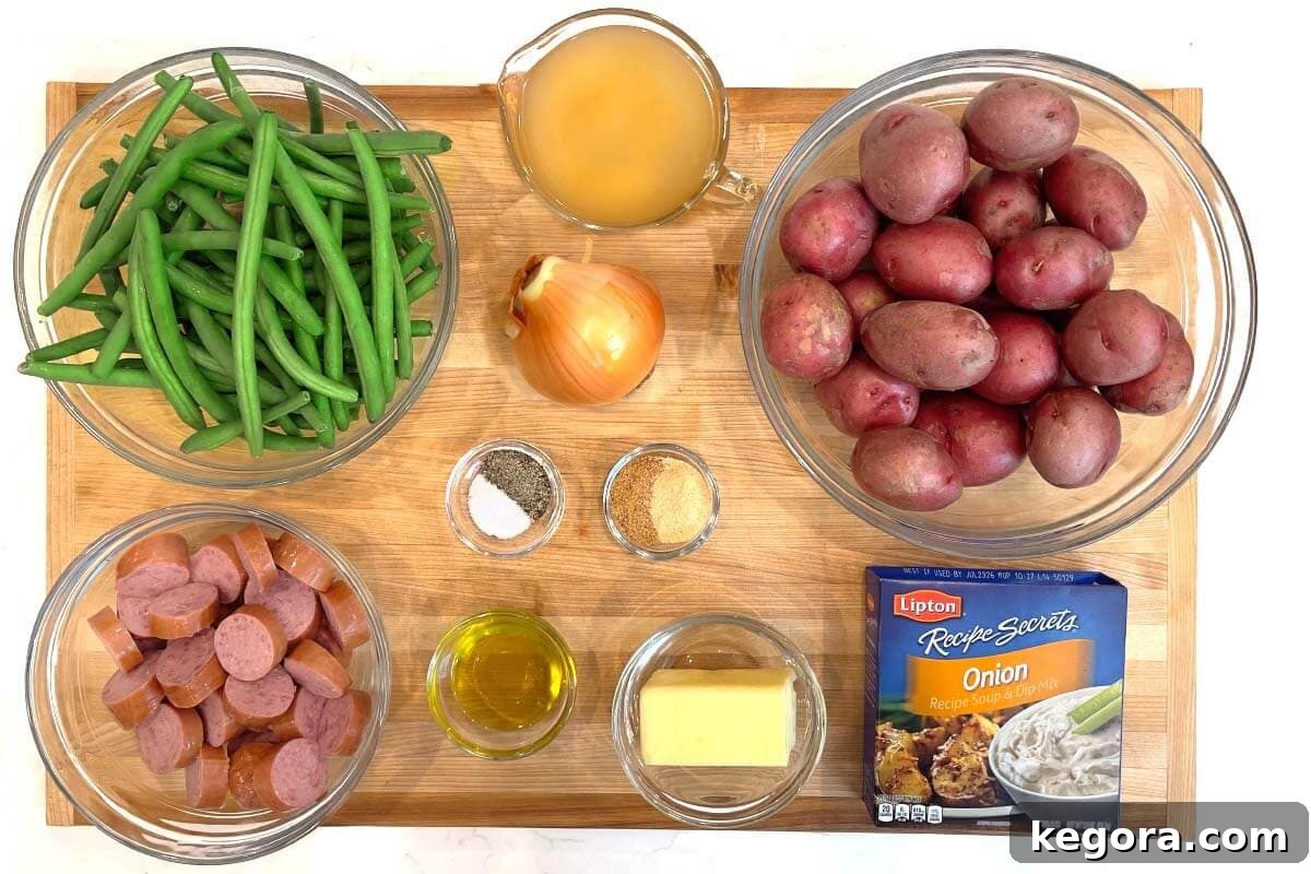 Arrangement of fresh ingredients for slow cooker Swamp Potatoes, including red potatoes, yellow onion, fresh green beans, and smoked sausage.