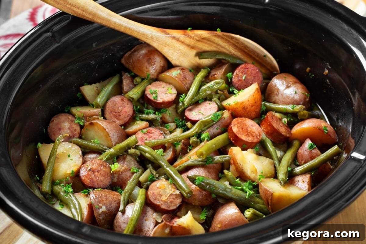 A hearty serving of Crockpot Swamp Potatoes in a bowl, featuring tender potatoes, sliced smoked sausage, and vibrant green beans.