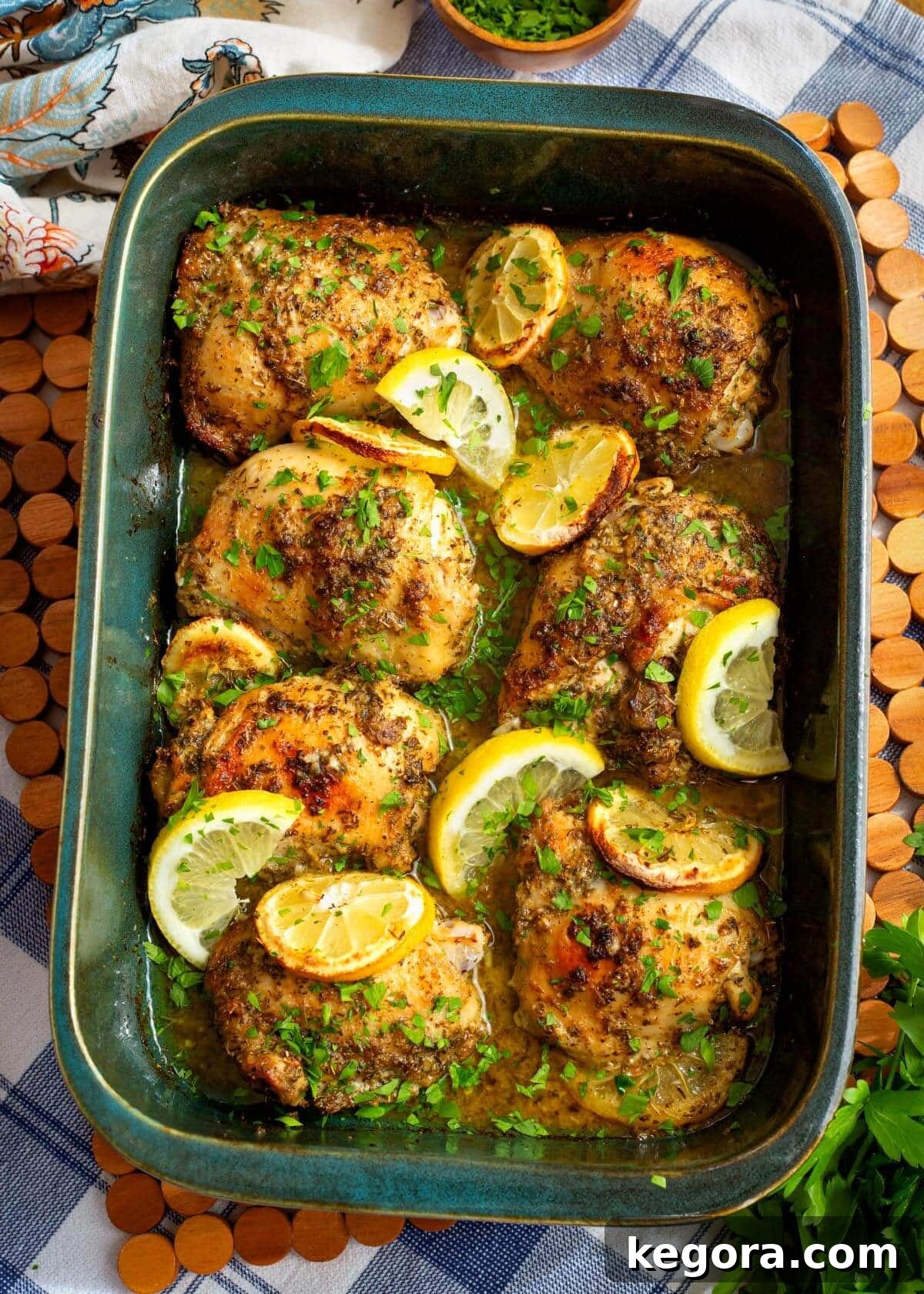 Zesty Greek Chicken Thighs 2 Golden brown Greek Lemon Chicken Thighs on a platter, garnished with fresh herbs and lemon slices.