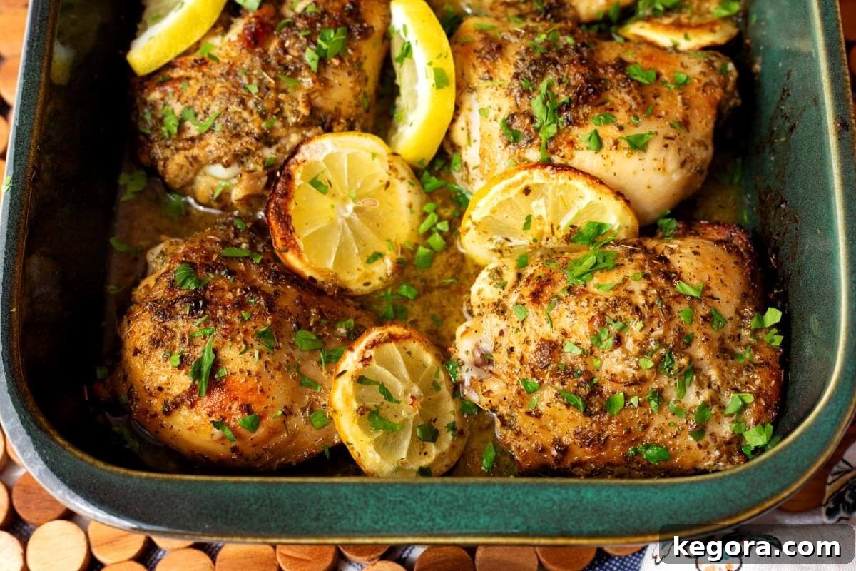 Zesty Greek Chicken Thighs 9 A vibrant platter featuring cooked Greek Lemon Chicken Thighs, surrounded by fresh herbs, lemon wedges, and cherry tomatoes, showcasing a complete meal.