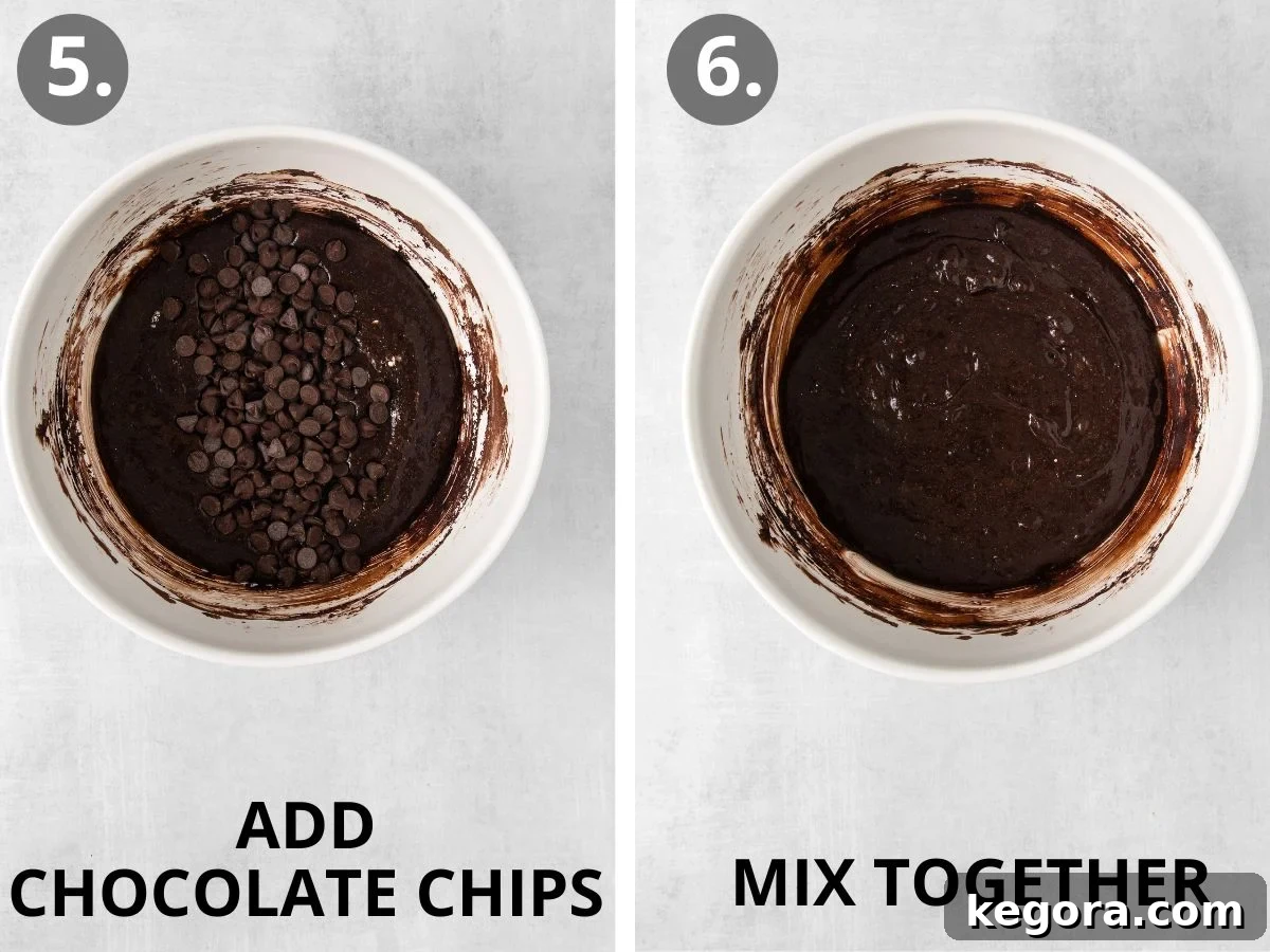 Additional chocolate chips being folded into the brownie batter in the bowl, creating a rich and thick consistency