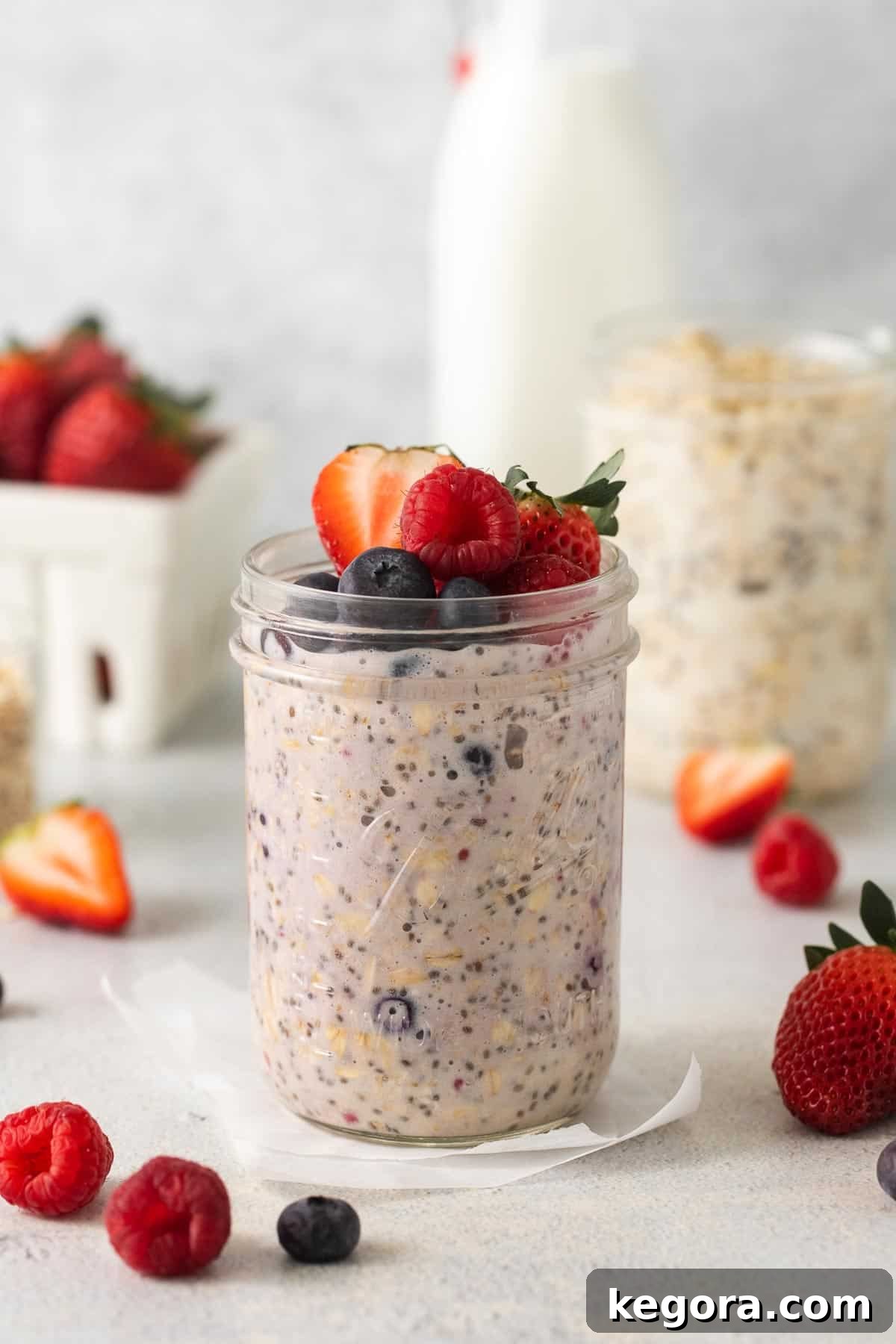 Berries and cream overnight oats in a jar, topped with fresh berries and a spoon