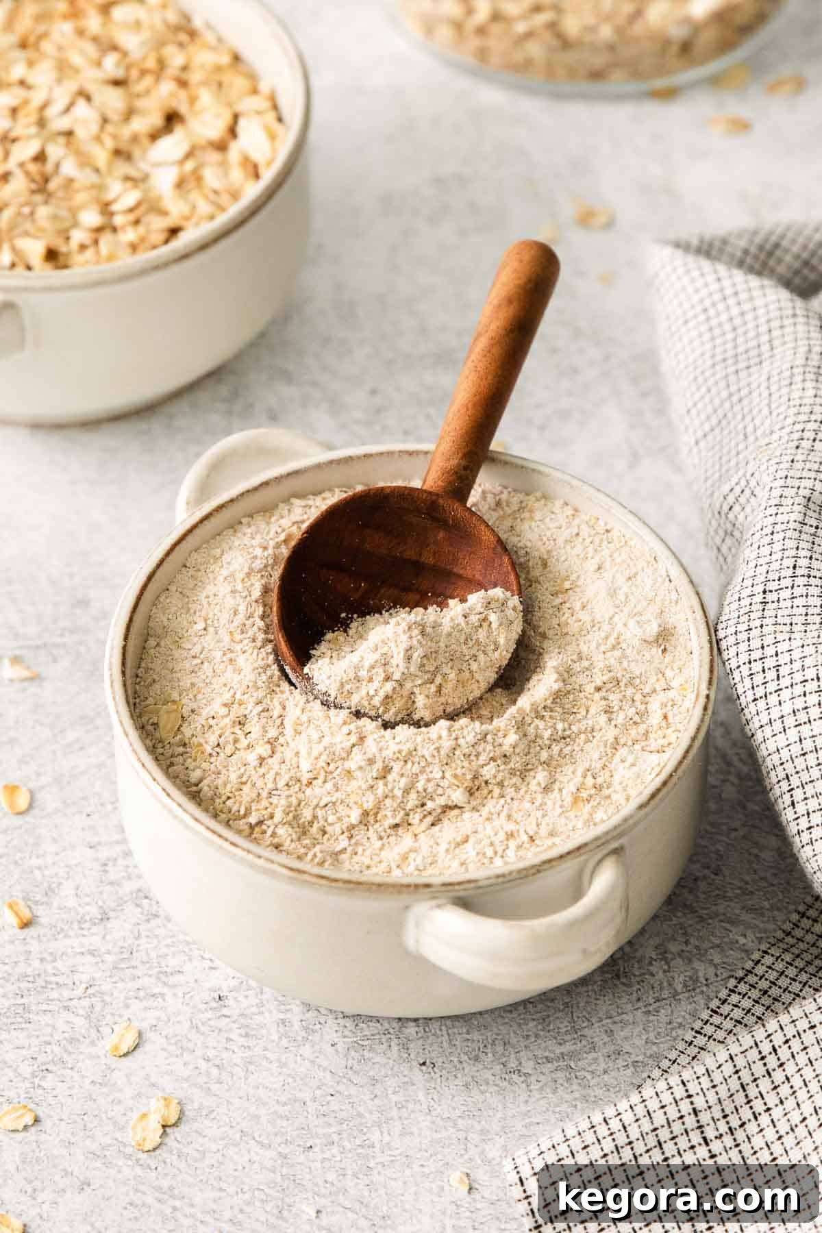 Gluten-free oat flour in a bowl with a wooden spoon in it