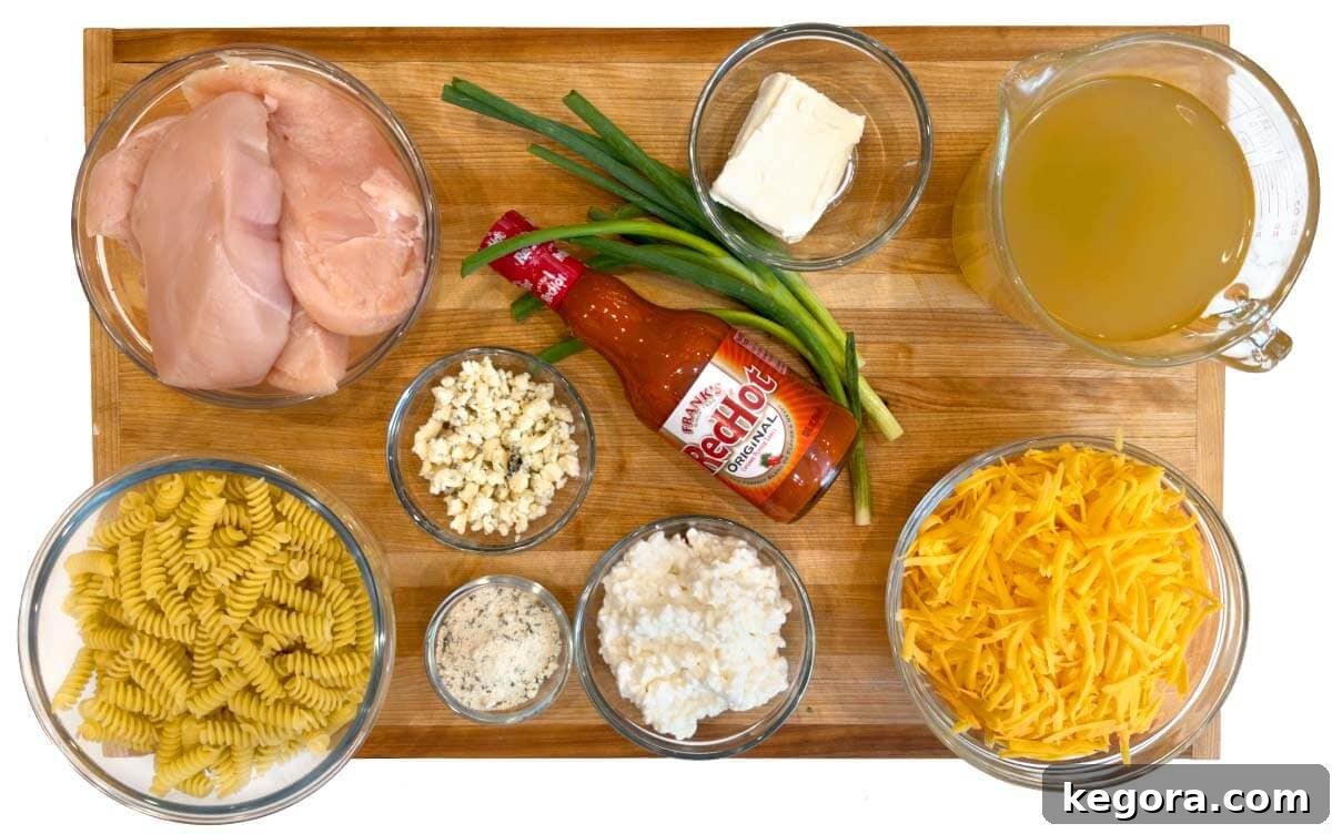 All ingredients for Crockpot Buffalo Chicken Mac and Cheese laid out on a wooden board