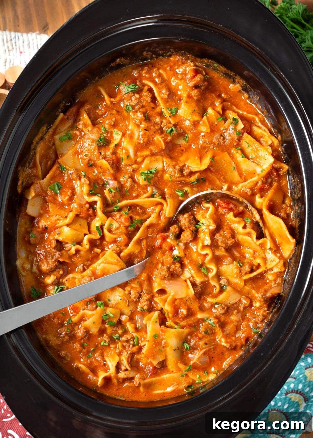 Effortless Slow Cooker Lasagna Soup 2 A steaming bowl of Crockpot Lasagna Soup with a dollop of creamy ricotta-Parmesan topping and fresh parsley garnish.