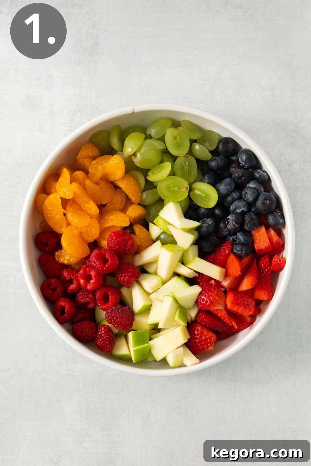 Festive Easter Fruit Delight 5 Chopped fresh fruits, including strawberries, blueberries, raspberries, and grapes, mixed in a large glass bowl.