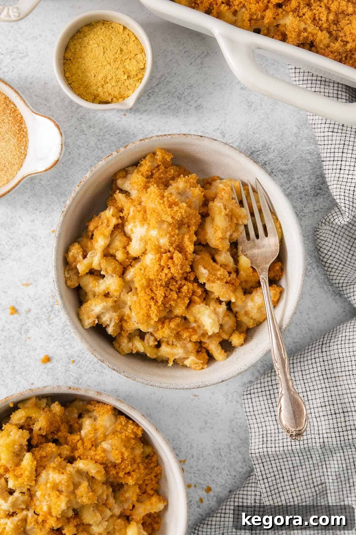 Vegan Mac and Cheese 3 A close-up shot of creamy dairy-free mac and cheese in a rustic bowl with a fork, showing the rich texture and golden breadcrumb topping.