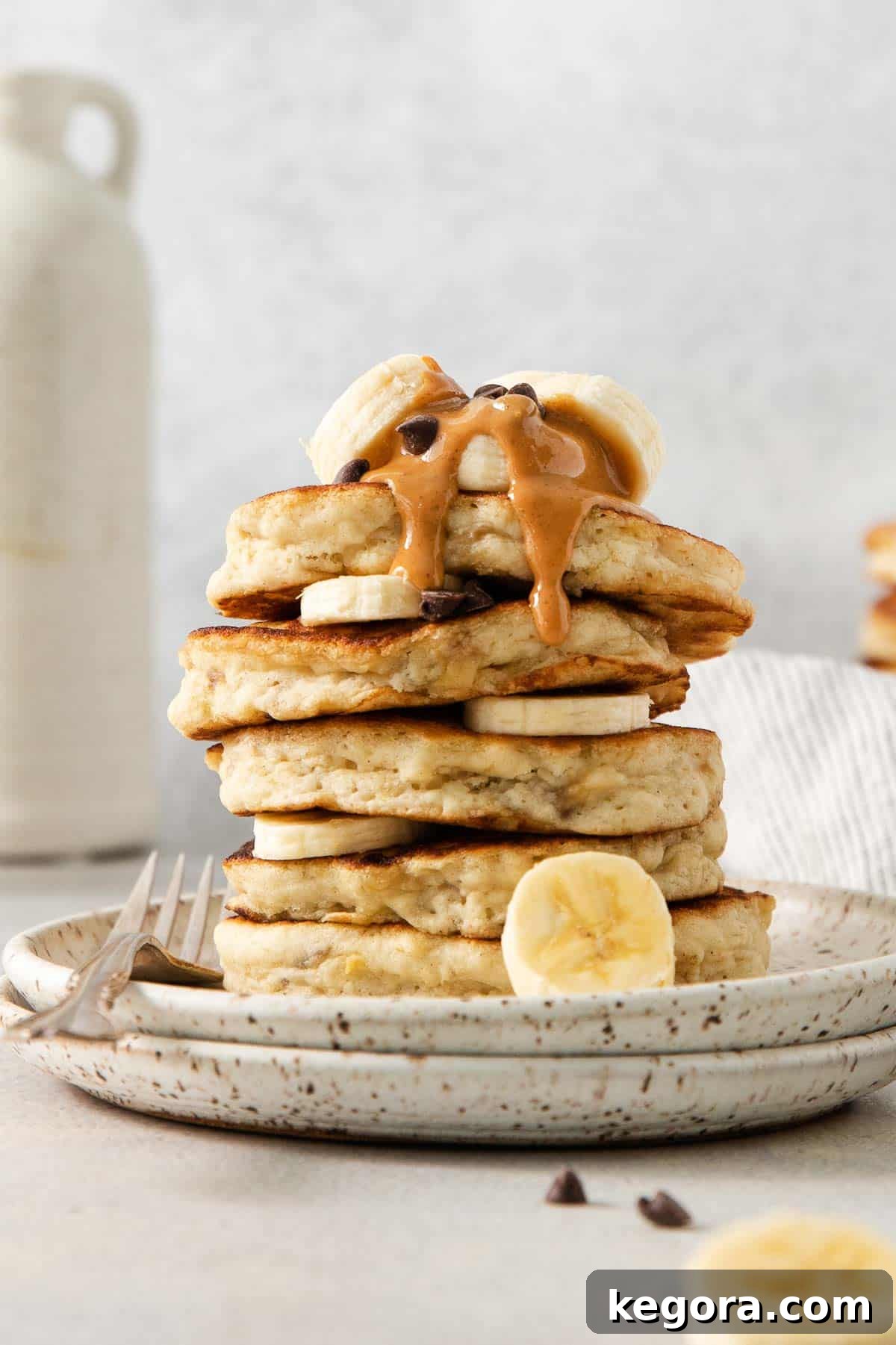 Naturally Sweet Gluten-Free Banana Hotcakes 2 Gluten-free banana pancakes stacked on a plate with a drizzle of peanut butter and banana slices on top, a perfect healthy breakfast.