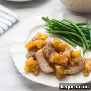 Pork tenderloin medallions with applesauce and green beans on a white plate.