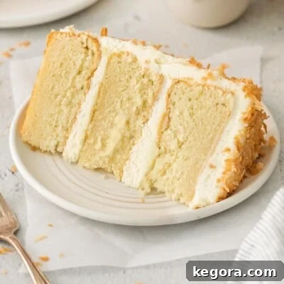 A generous slice of gluten-free coconut cake on a white plate.
