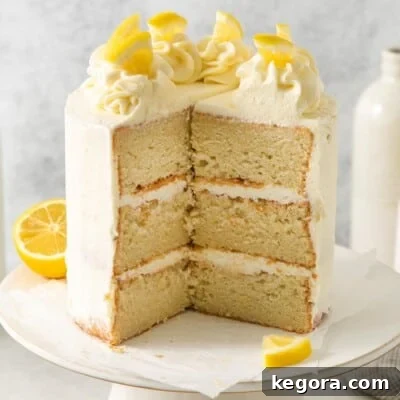A stunning gluten-free lemon layer cake on an elegant cake stand, with a generous slice removed, garnished with fresh lemon slices and zest.