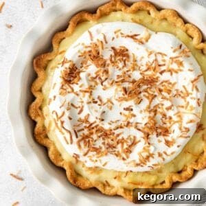 A delicious closeup of a dairy-free coconut cream pie, showcasing its smooth, creamy filling, toasted coconut flakes, and light whipped topping.