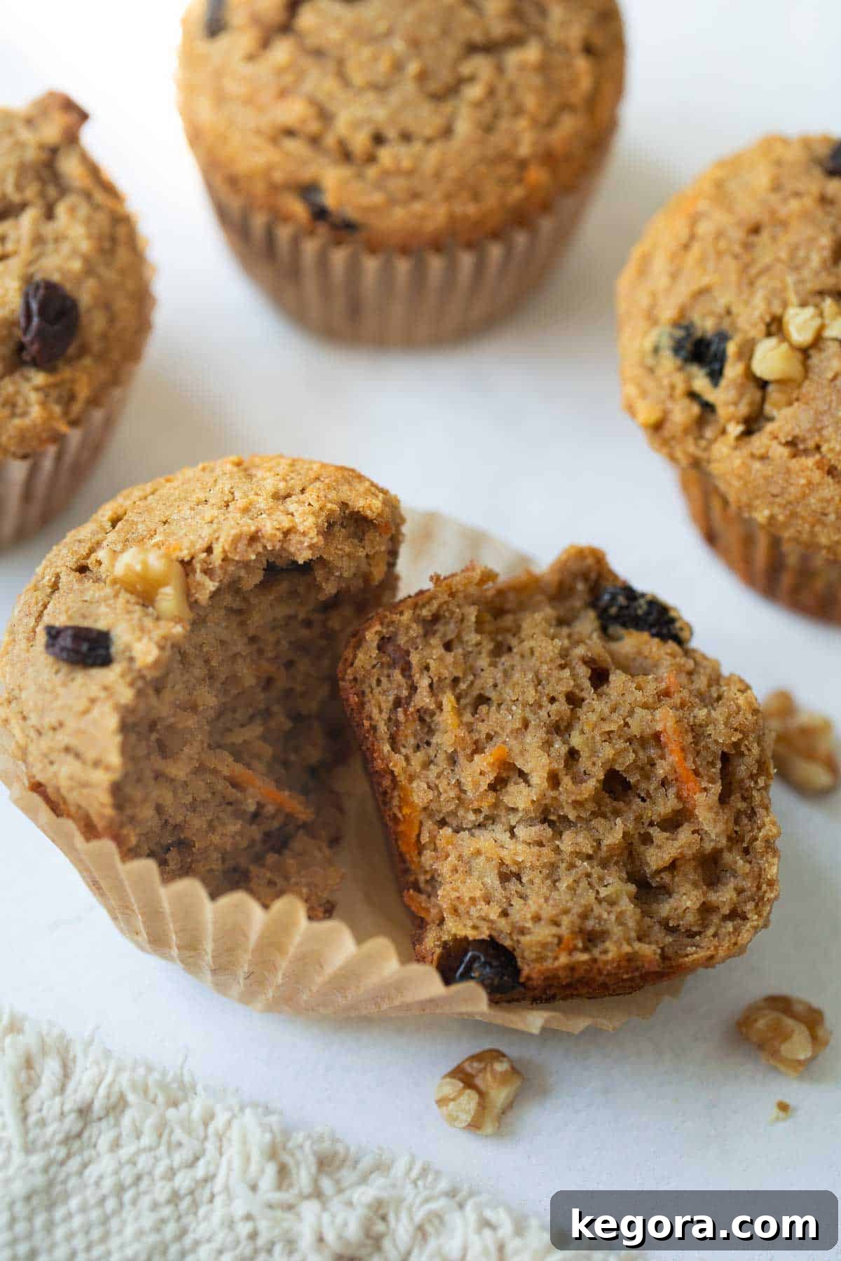 Buckwheat muffin cut in half showing its wholesome interior, with whole muffins in the background