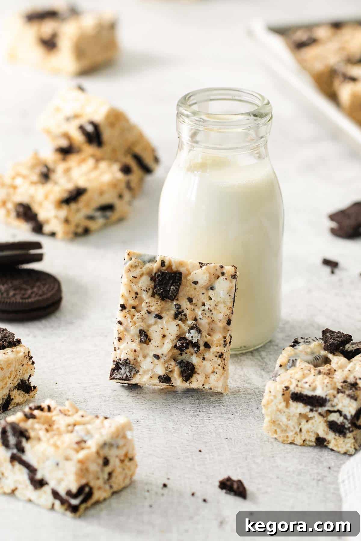 Gluten-Free Oreo Crunch Bars 8 Gluten-free Oreo rice crispy treats stacked on a wooden board next to a glass jar of milk, ready to be enjoyed