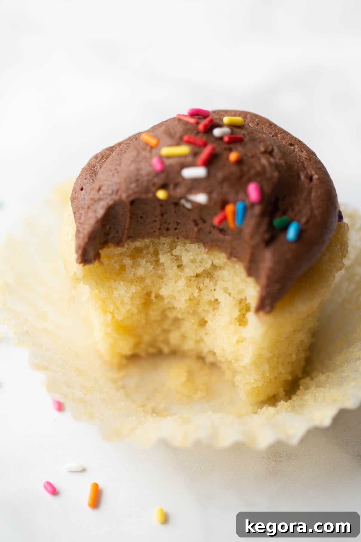 A close-up shot of a gluten-free cupcake with a bite taken out, revealing its moist and tender interior.
