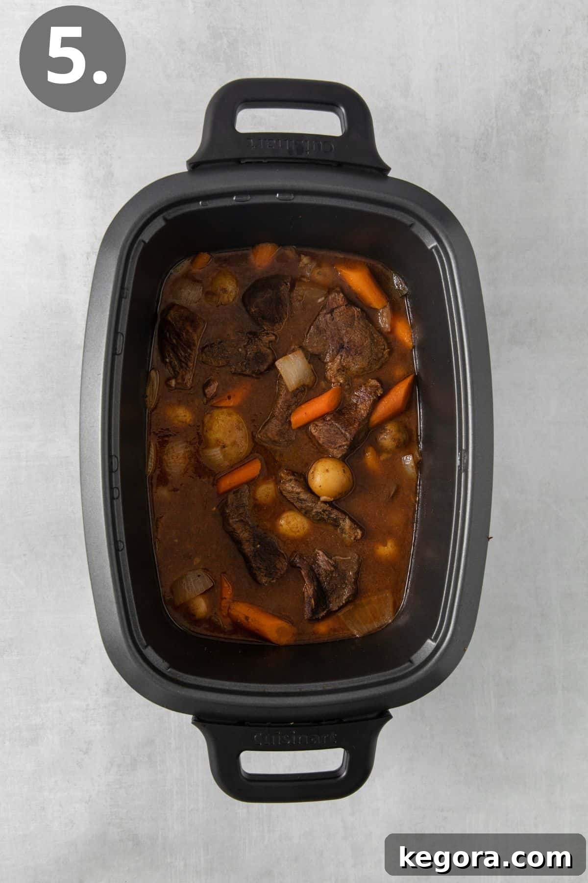 Cooked roast, carrots, onions, and potatoes in a slow cooker, ready to serve