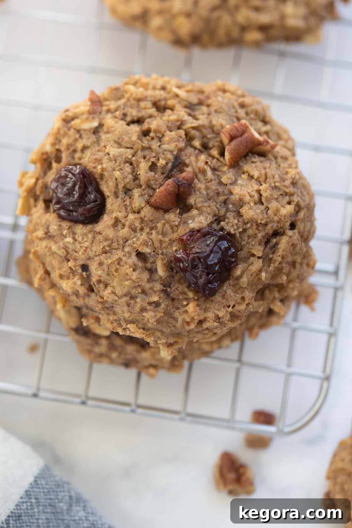 Close-up of a perfectly baked oatmeal cookie, showing bananas, raisins, and nuts embedded within for a hearty texture.