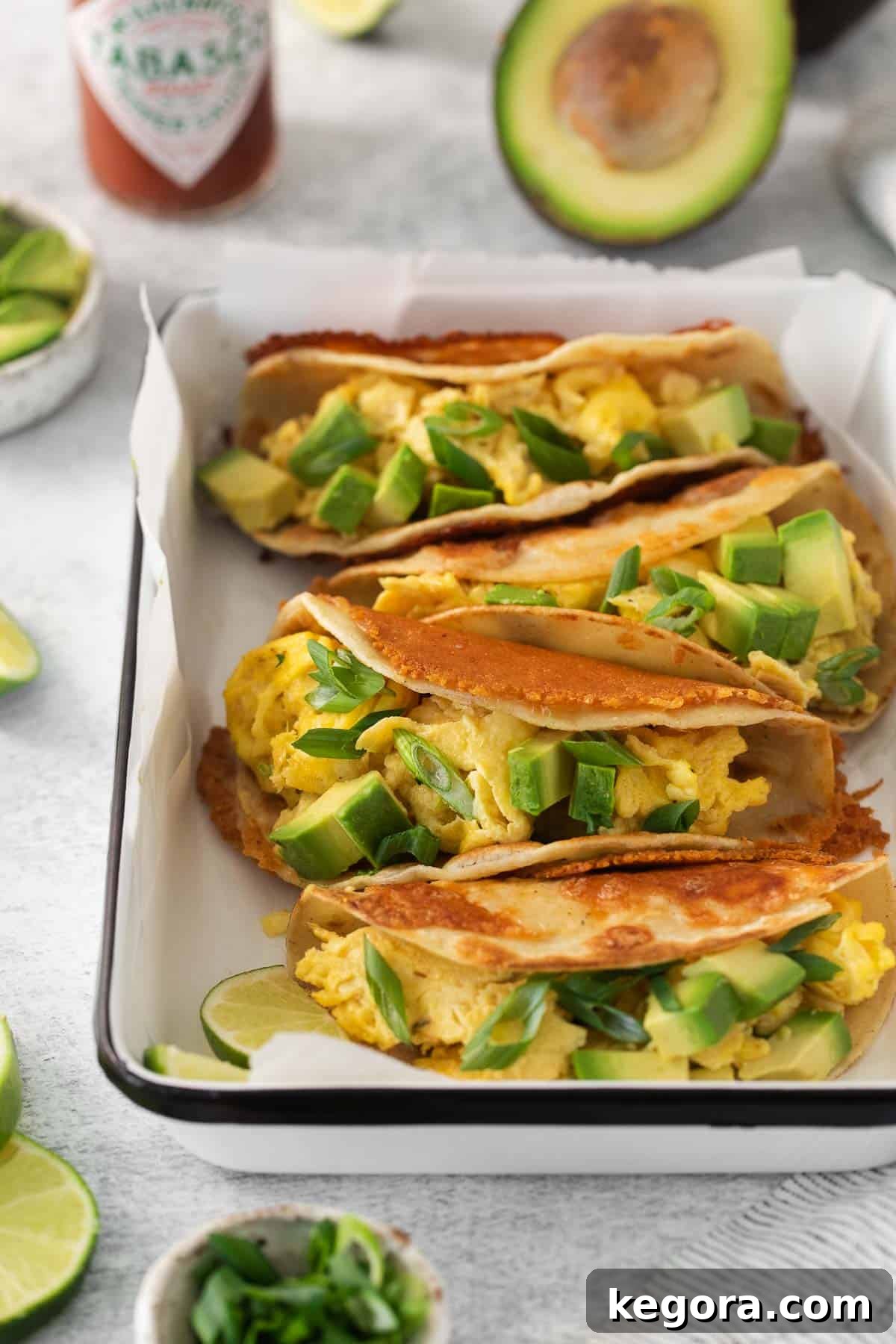 An inviting overhead shot of breakfast tacos artfully arranged in a baking dish, nestled on a bed of parchment paper, highlighting their vibrant colors and appealing textures.