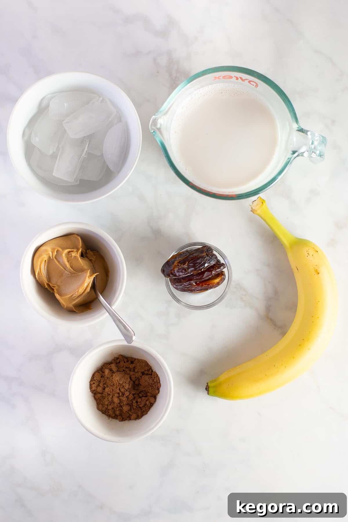 chunky monkey smoothie ingredients Key ingredients for a chunky monkey smoothie, including almond milk, ripe bananas, rich cocoa powder, creamy peanut butter, and sweet dates, laid out on a surface.