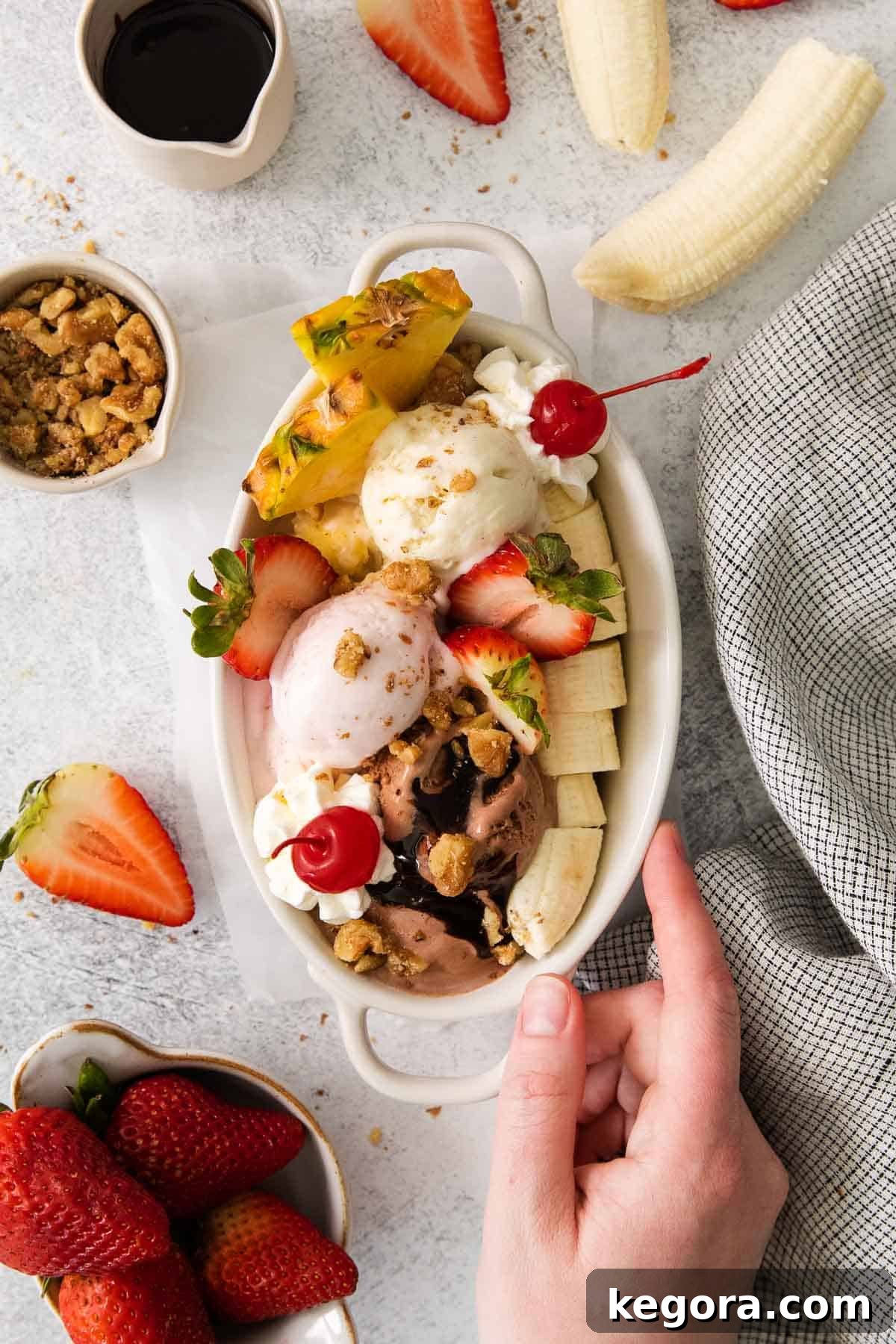 Timeless Banana Split Indulgence 9 Banana split in a dish with a hand touching the dish