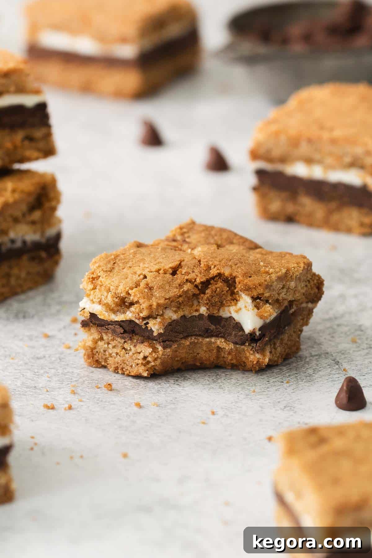 A perfectly baked gluten-free s'mores bar on a countertop with a bite taken out, showcasing the gooey chocolate and marshmallow layers.