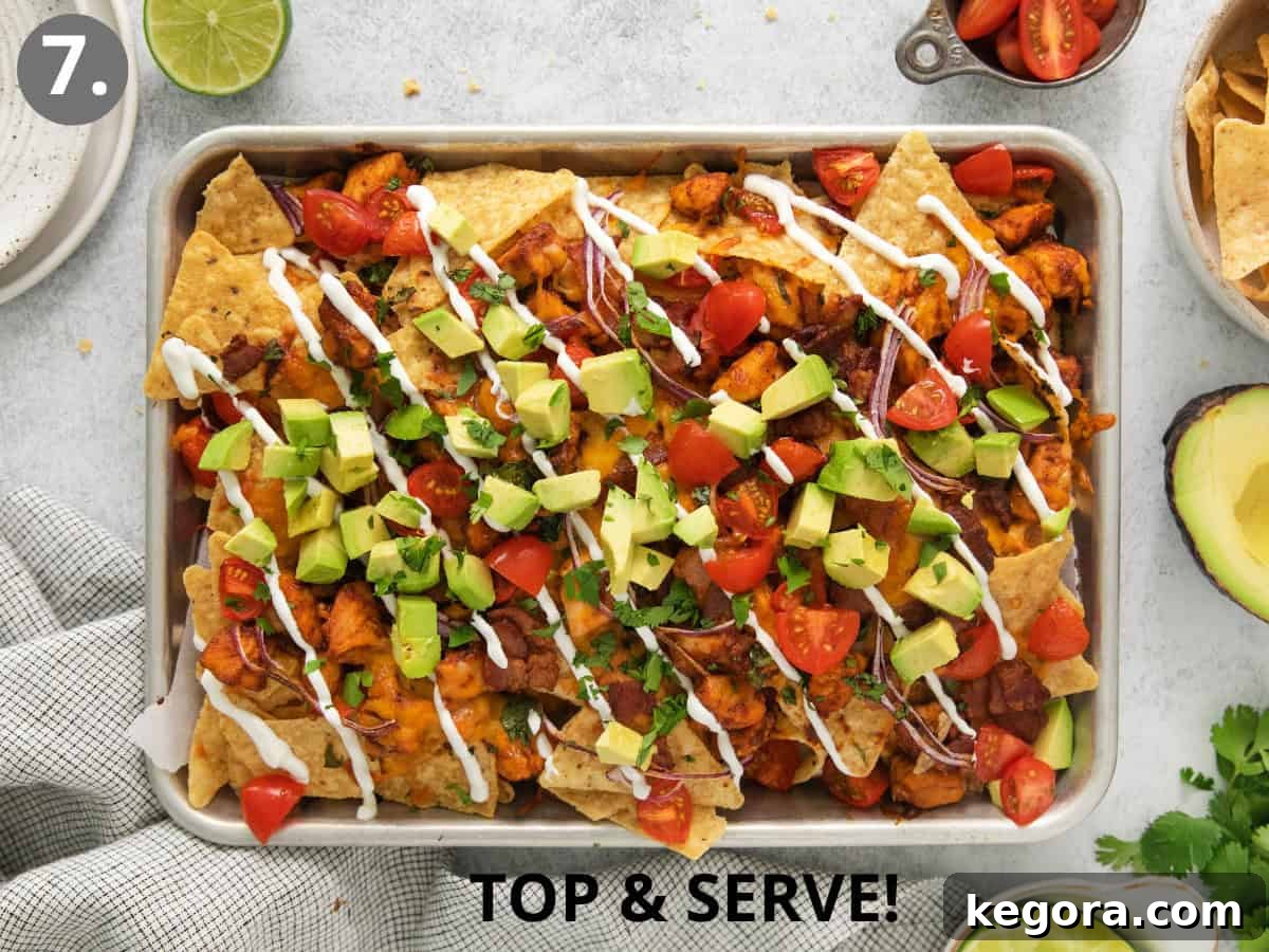 Ultimate BBQ Chicken Nachos 8 Finished BBQ chicken nachos spread on a sheet pan, garnished with fresh cilantro, avocado, and a drizzle of sour cream, ready to be served.