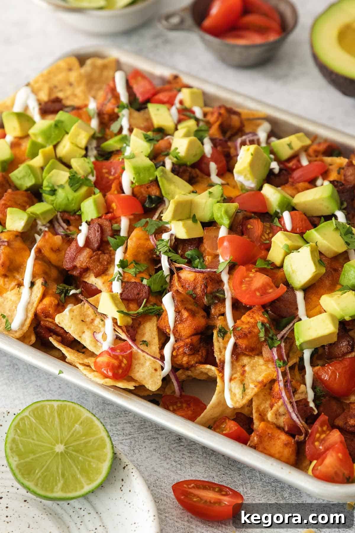 Ultimate BBQ Chicken Nachos 9 A vibrant close-up photo of BBQ chicken nachos generously loaded with toppings on a sheet pan, showcasing melted cheese and fresh garnishes.
