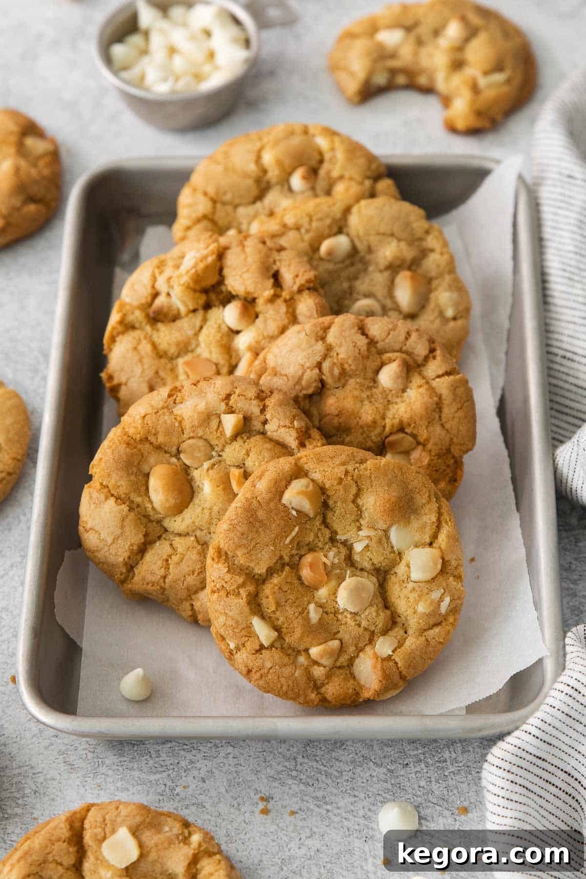 Freshly baked gluten-free white chocolate macadamia nut cookies cooling on a baking tray lined with parchment paper, showcasing their golden edges and soft centers.