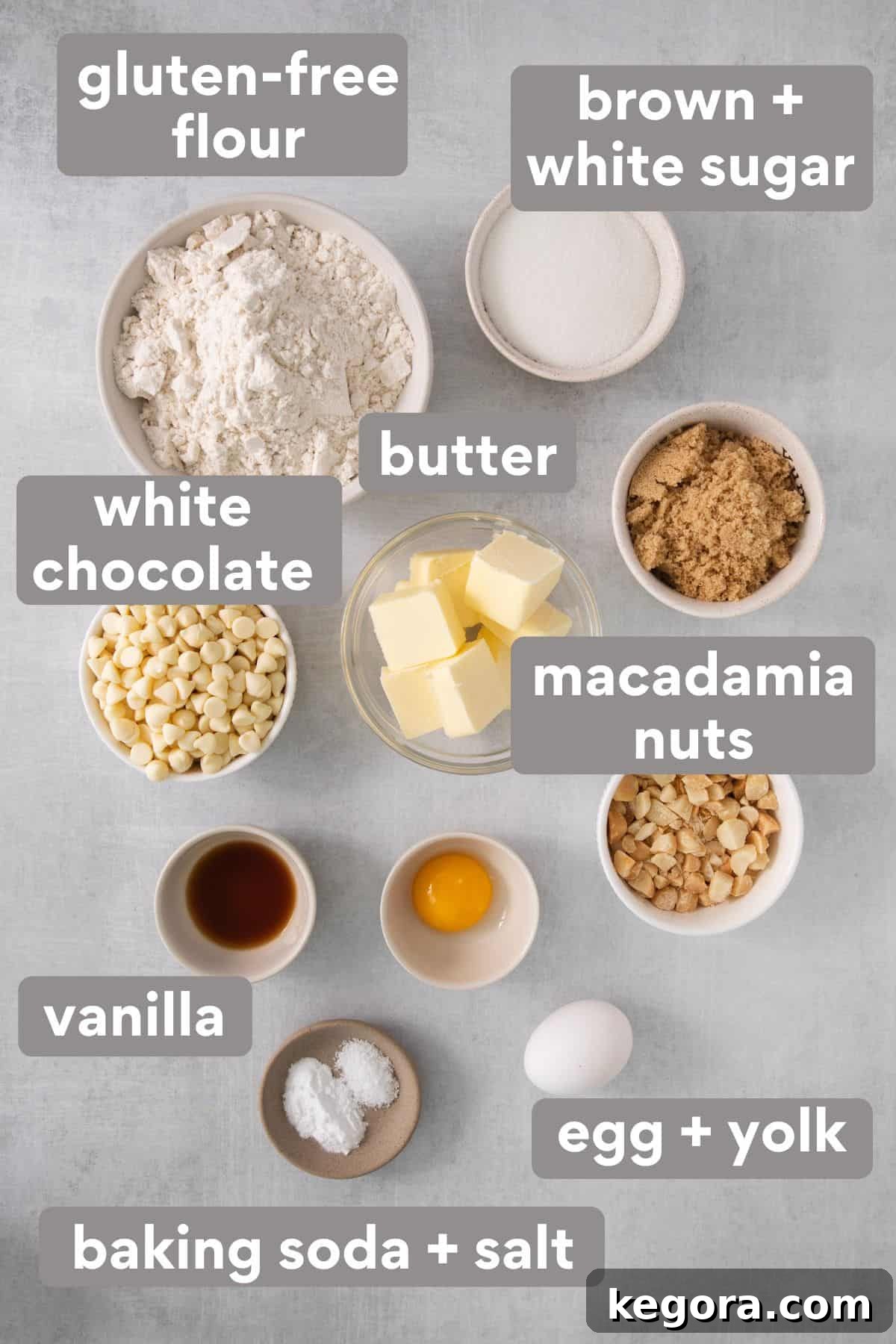 Carefully arranged ingredients for gluten-free white chocolate macadamia nut cookies on a kitchen countertop, including flour, sugars, butter, eggs, vanilla, white chocolate chips, and macadamia nuts.