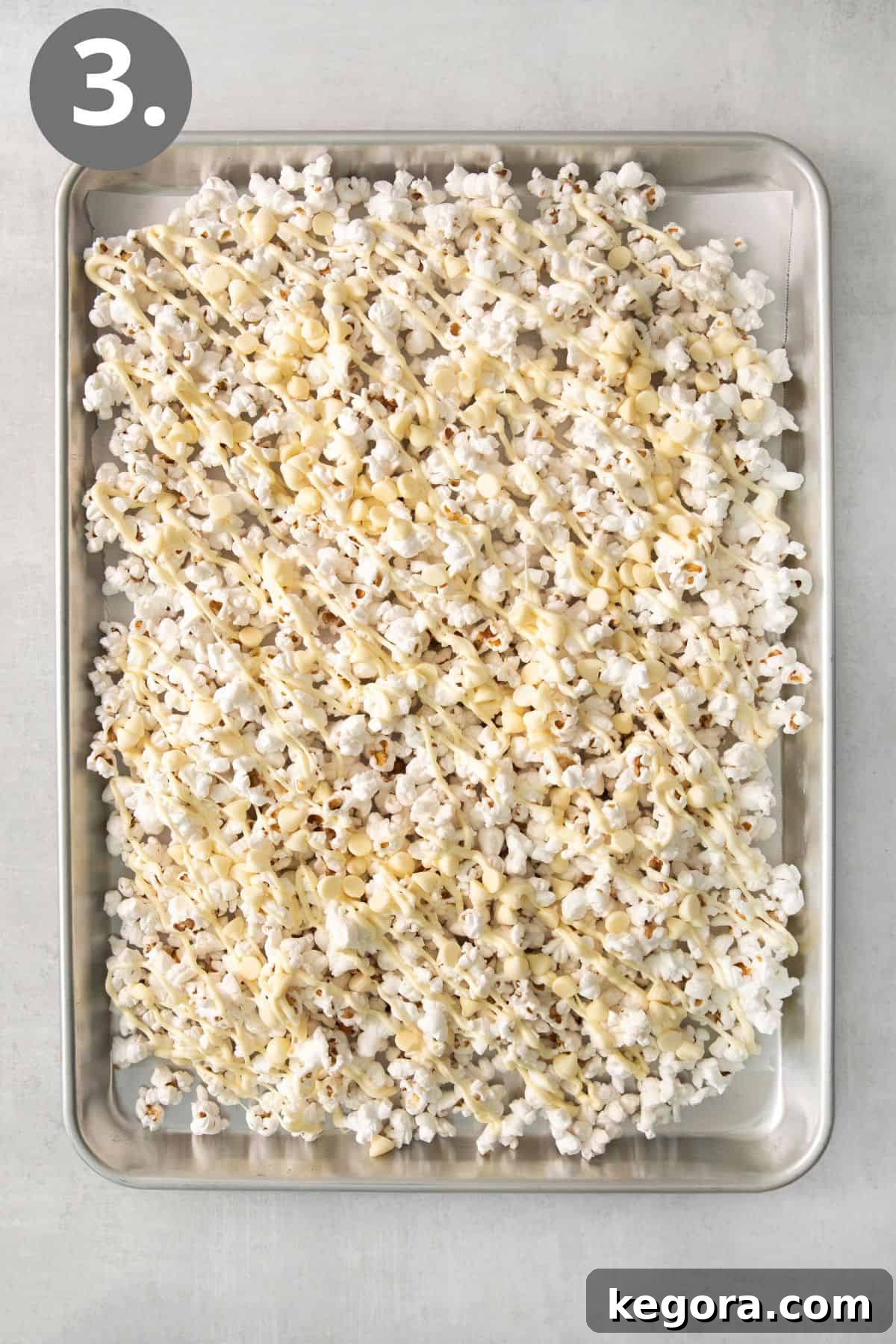 Gourmet White Chocolate Pop 6 White chocolate being drizzled over popcorn on a baking tray
