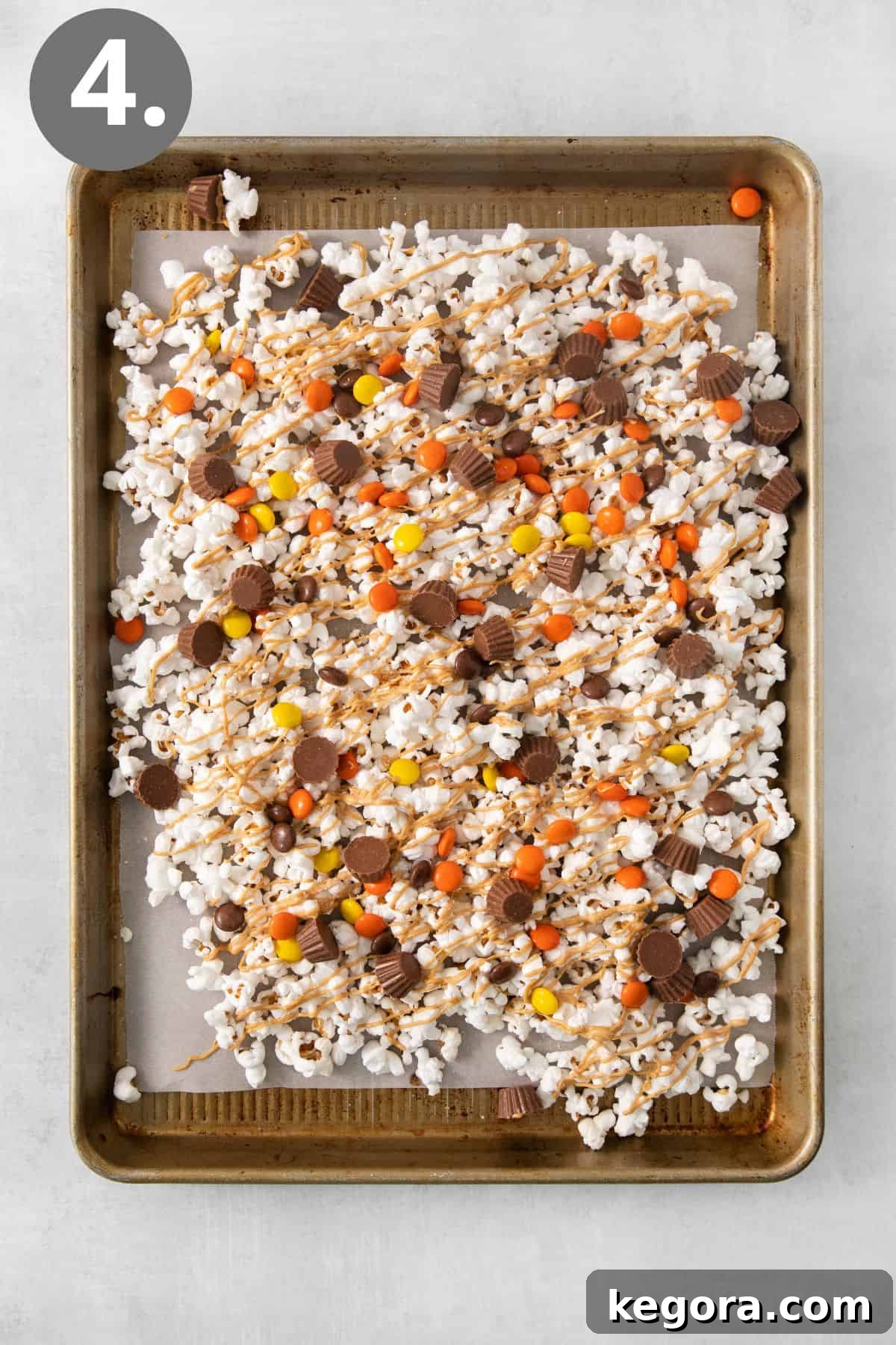 Nutty Caramel Popcorn 7 Peanut butter popcorn on a sheet pan, with Reese's Pieces and cups scattered over it