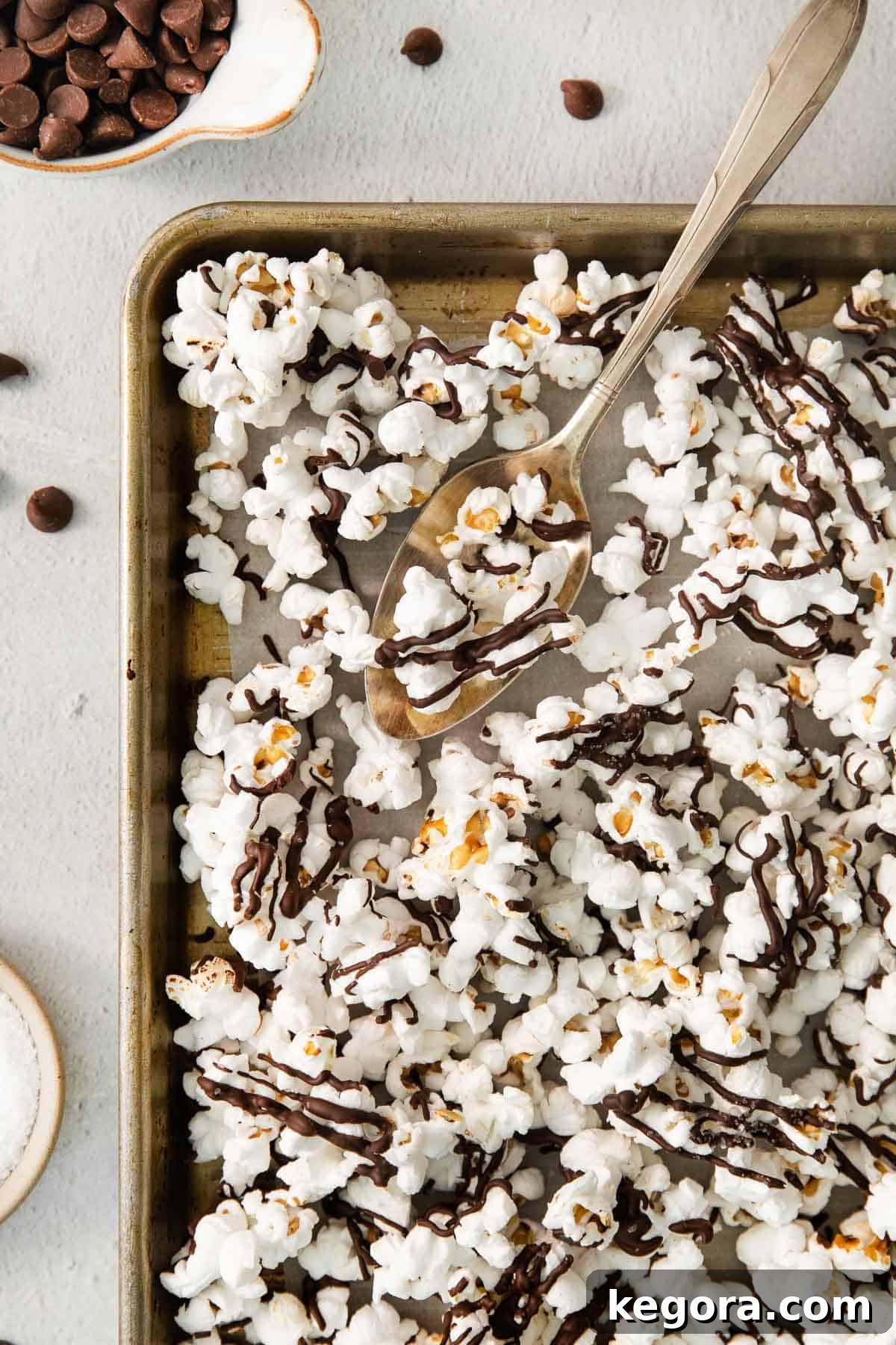 The Gluten-Free Truth About Popcorn 3 Delicious chocolate drizzle popcorn on a white baking sheet, a perfect example of a flavored popcorn treat.