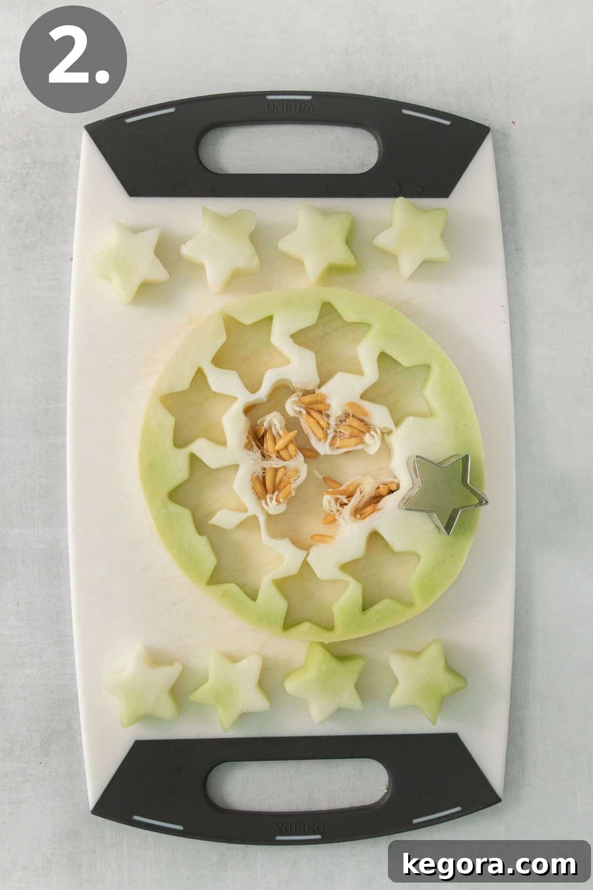Red White and Blue Fruit Celebration 5 Honeydew melon slices carefully cut into star shapes using a cookie cutter on a cutting board.