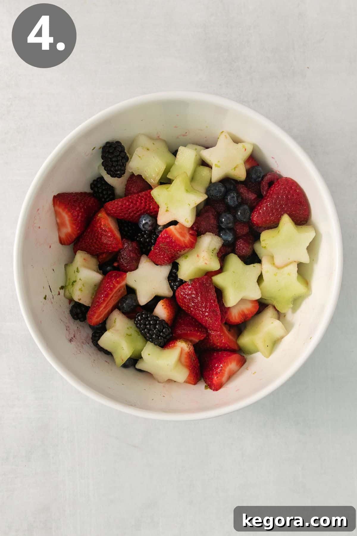 Red White and Blue Fruit Celebration 7 The 4th of July fruit salad, now tossed with the honey-lime dressing, glistening and ready to serve in a large glass bowl.