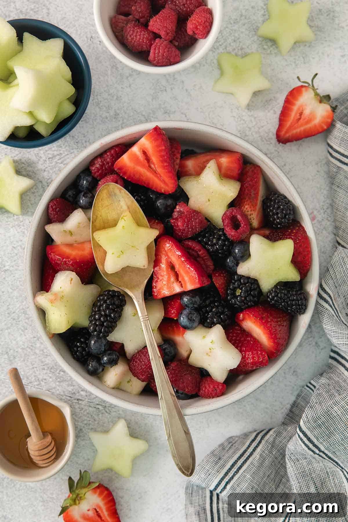 Red White and Blue Fruit Celebration 9 A close-up of the Fourth of July fruit salad in a bowl, with a serving spoon scooping out a portion, highlighting the vibrant colors and textures.