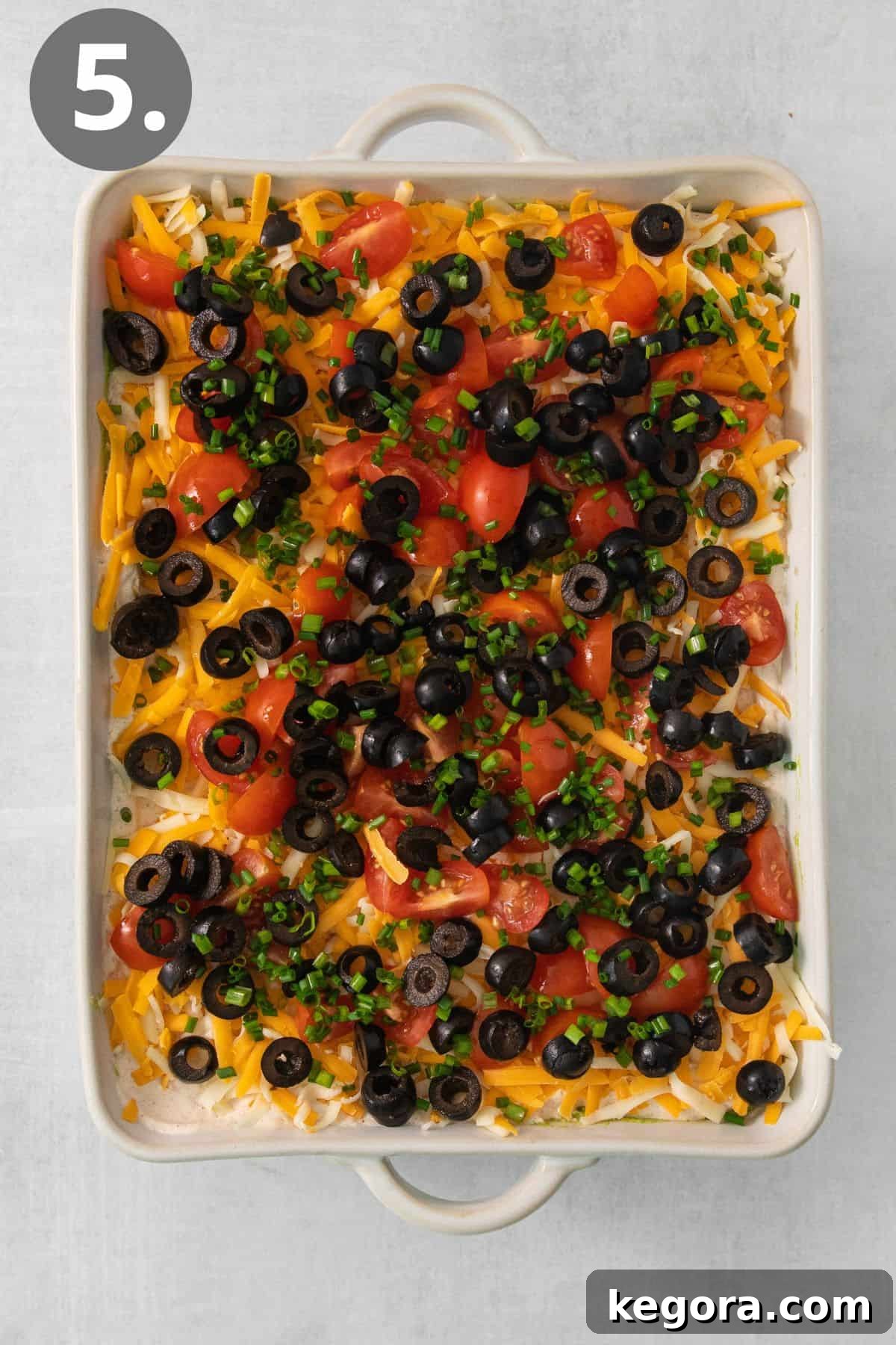 A beautifully assembled 7-layer taco dip in a clear baking dish, showcasing all its distinct, colorful layers, ready to be served.