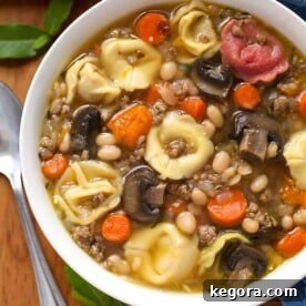 Effortless Instant Pot Mini Tortellini Soup 4 Instant Pot Tortellini Soup in a white bowl on a wooden board with a spoon, ready to be enjoyed.