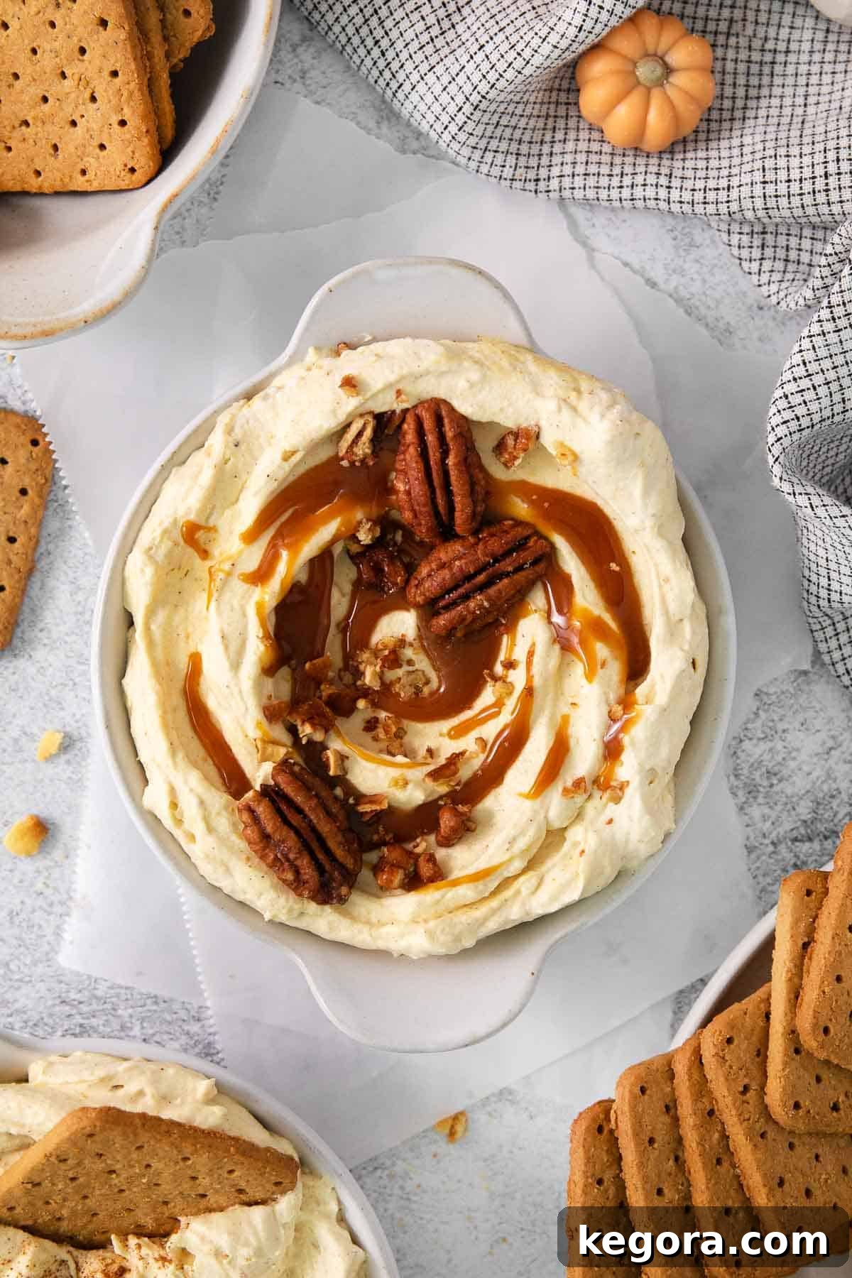 Pumpkin cheesecake dip topped with caramel and pecans in a serving bowl, ready to be enjoyed.