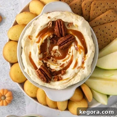 Pumpkin cheesecake dip served on a platter with cookies, graham crackers, and apple slices for dipping.