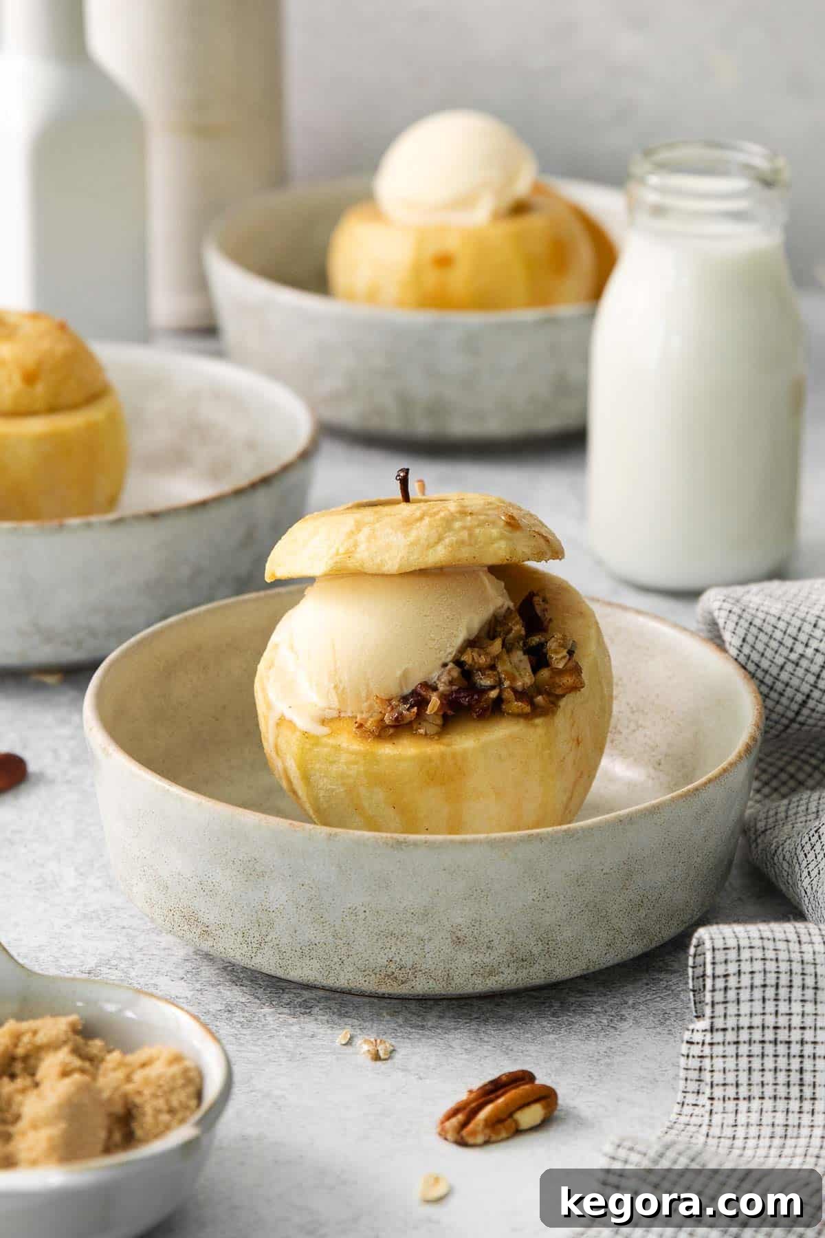Comforting Gluten-Free Baked Apples 6 A perfectly baked apple with a rich brown sugar pecan filling, a scoop of melting vanilla ice cream, and a drizzle of maple sauce on a white plate, ready to be enjoyed.