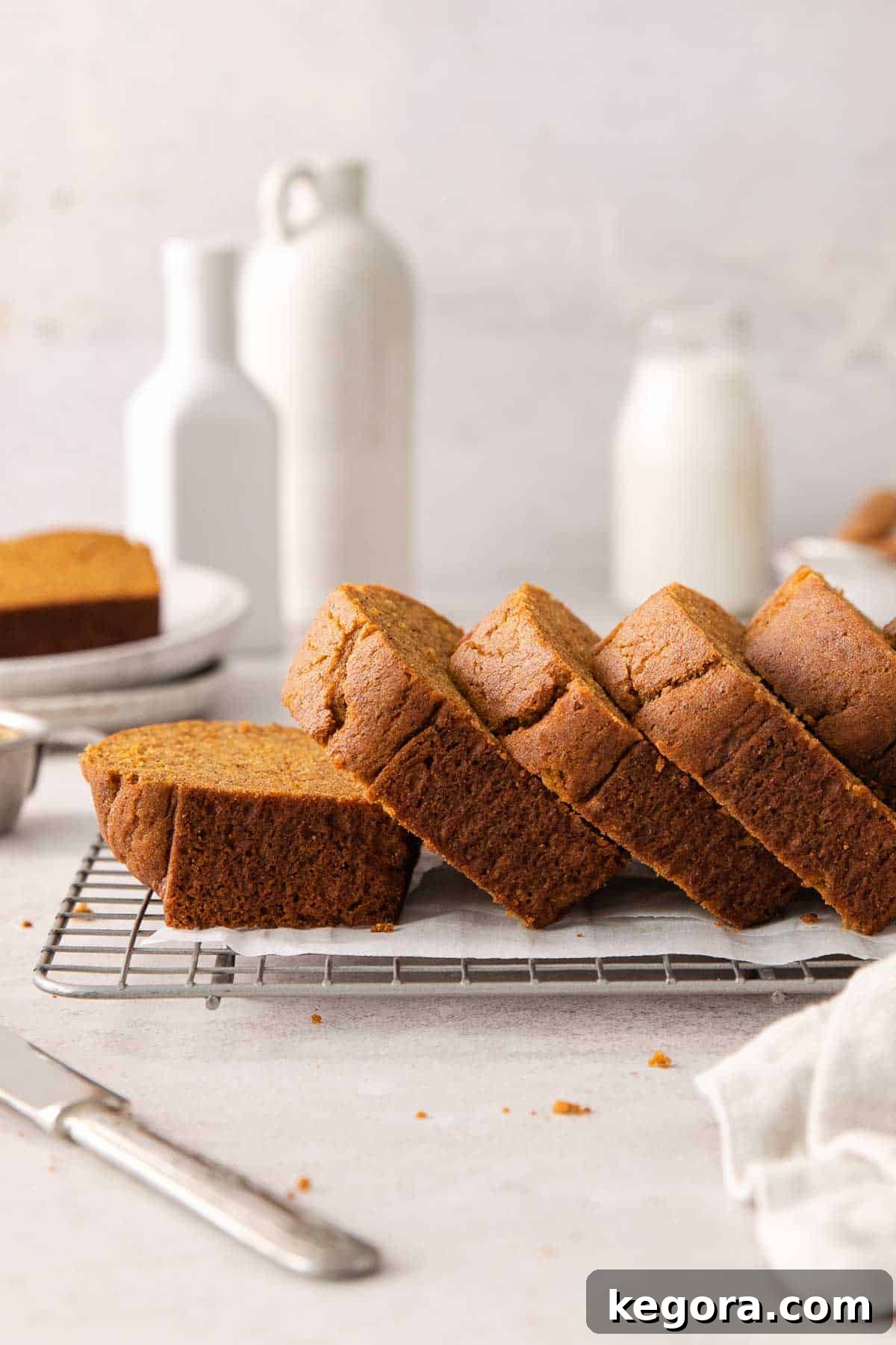 Cozy Gluten-Free Pumpkin Spice Loaf 11 A side view of baked gluten-free pumpkin bread sliced on a wire rack