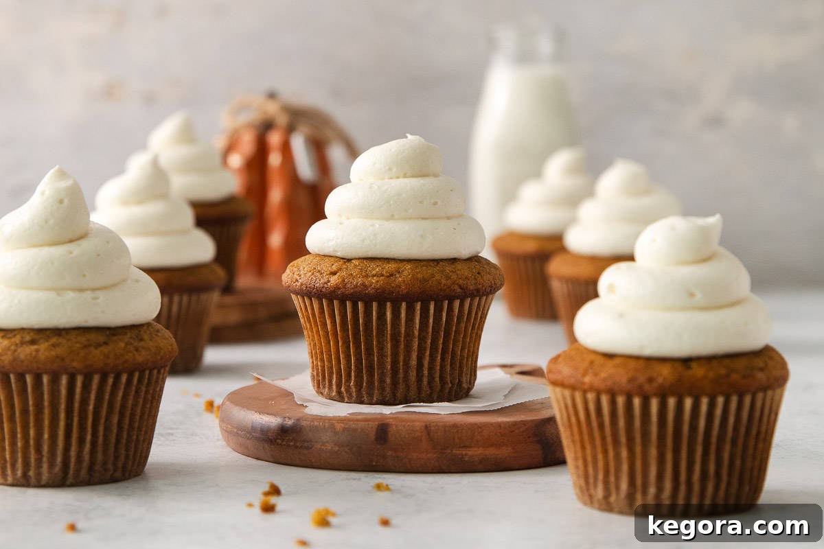 Beautifully frosted gluten-free pumpkin cupcakes on a countertop with a bottle of milk in the soft-focus background, ready for serving.