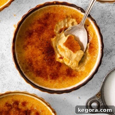 Pumpkin creme brulee in ramekins on a countertop, with a spoon in the ramekin