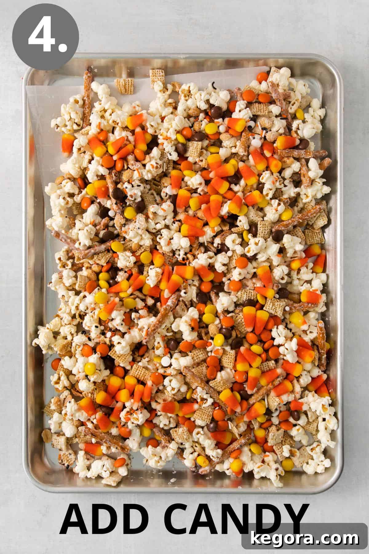 Monster Munch Mix 7 Halloween snack mix on a baking sheet, topped with Reese's Pieces, candy corn, and festive sprinkles.